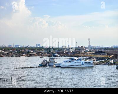 Jakarta, Indonesia - November 13, 2020 : Boats leaning on the reclaimed beach area, with a backdrop of fishing settlements on Pantai Indah Kapuk, Stock Photo