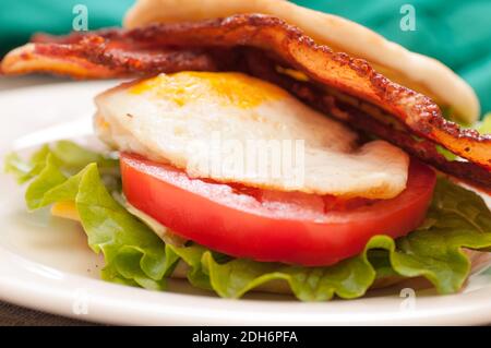 breakfast sandwich wiuth crispy bacon, farm fresh egg, tomato and lettuce on naan flatbread Stock Photo