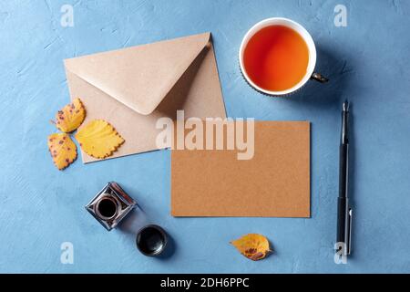 Autumn stationery mockup, a brown craft a5 card with an envelope, shot from the top with a cup of tea and ink pen Stock Photo