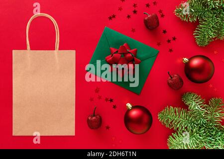 Kraft shopping bag mockup on Christmas styled background..Christmas tree branches, baubles, decorations on red Stock Photo