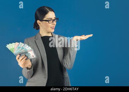 Beautiful young woman in glasses holds a lot of tenge money in her hand with copy space. Stock Photo