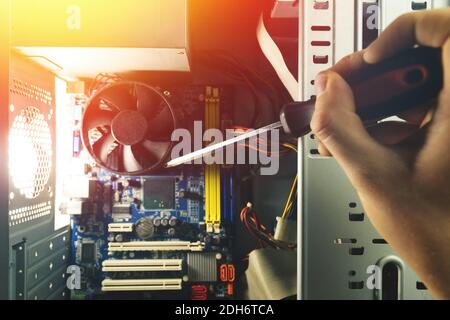 Close-up on the hands with screwdriver tool of the technician repairing a PC computer. Stock Photo