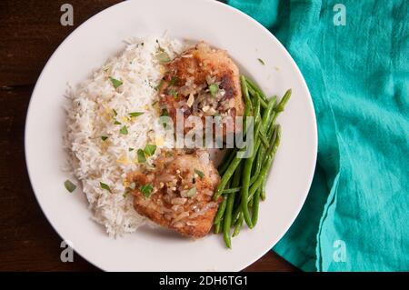 cripsy fried chicken thighs with vegetables over rice in a lemon sauce Stock Photo