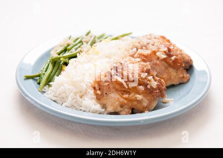 cripsy fried chicken thighs with vegetables over rice in a lemon sauce Stock Photo