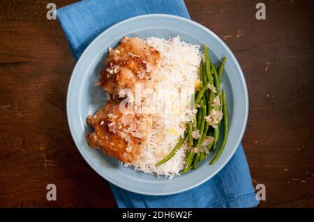 cripsy fried chicken thighs with vegetables over rice in a lemon sauce Stock Photo