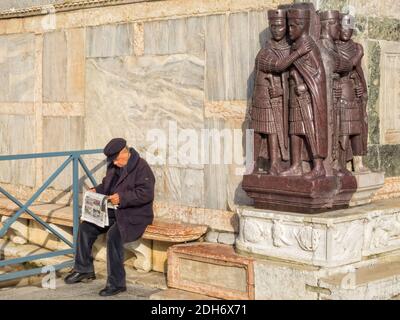 An elderly man is reading his newspaper on a quiet sunny  spot under the watchful eyes of the Tetrarchs - Venice, Veneto, Italy Stock Photo