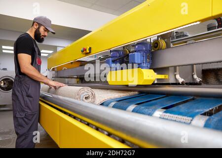 Man operating carpet automatic washing machine in professional laundry service Stock Photo