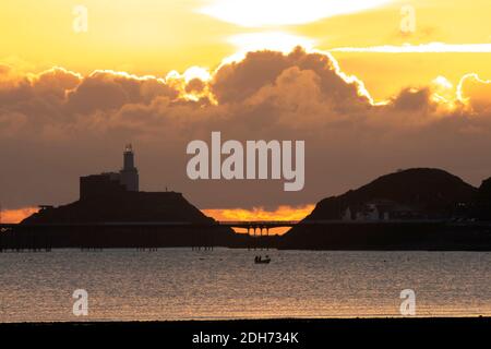 Sunrise over The Mumbles Swansea Bay. A fisherman sets his nets Stock Photo