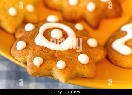 Closeup gingerbread cookies for christmas holiday on the yellow plate and gray checkered background. Holiday concept Stock Photo