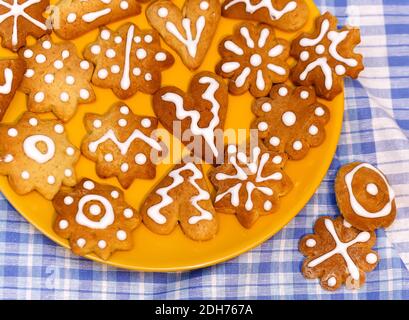 Gingerbread cookies for christmas holiday on the yellow plate and white blue checkered background. Holiday concept Stock Photo