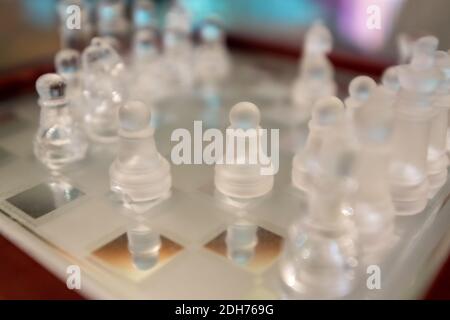 Glass chess figurines playing game on chess board Stock Photo