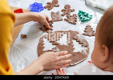 Mother and baby together cut out cookies from the dough. Top view from the shoulder. Close up of table. Christmas concept and family cooking meals wit Stock Photo