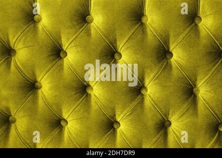 Quilted velour buttoned Illuminating yellow color fabric wall pattern background. Elegant vintage luxury bright golden mustard colour sofa upholstery Stock Photo