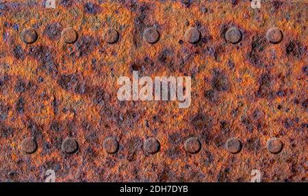 Old rusty stained metal sheet with two rows of rivets close up, metal texture or background Stock Photo