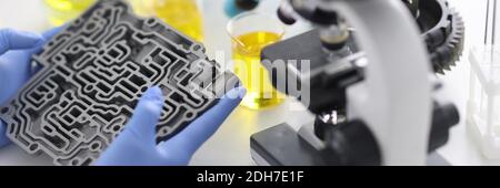 Automatic transmission lies in rubber gloves on table with microscope and test tubes in chemical laboratory closeup Stock Photo
