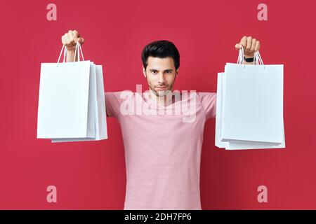 Young handsome man holding shopping bags in hands isolated over red background Stock Photo