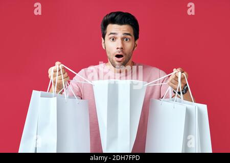 Young surprised man holding shopping bags in hands and looking his purchase Stock Photo