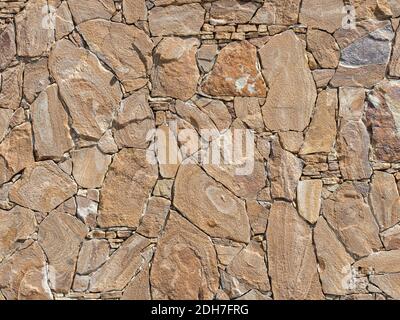 A decorative exterior wall with rough stonework lined in a chaotic manner. Background texture Stock Photo