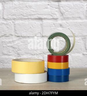 Stack of colorful insulating tape on white brick wall background Stock Photo