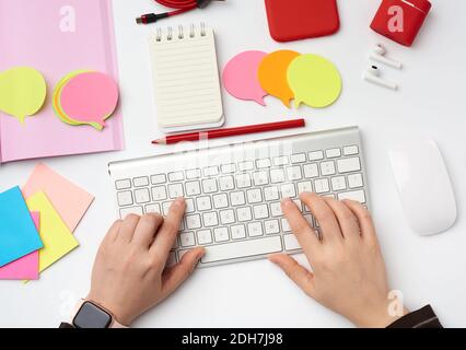 Two female hands and a white keyboard, freelancer workplace with an open notebook, headphones Stock Photo