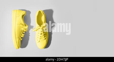 Banner with yellow female gumshoes on grey background. View from above. Space for text. Trendy color Ultimate Grey and Illuminating of the 2021 year. Stock Photo