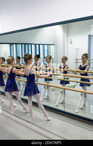 Little ballerinas using barre while practicing in dance studio.Ballerinas are all dressed for class in matching leotards, tights and ballet slippers. Stock Photo