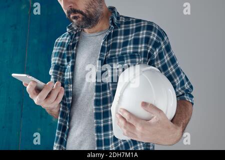 Construction engineer using mobile phone on a morning break, relaxing and preparing for work Stock Photo