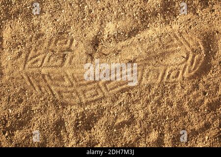 A closeup shot of an imprint of a shoe on a sandy ground with black ants Stock Photo