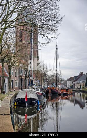 Oudewater, The Netherlands, December 6, 2020: view along the quay of Hollandsche IJssel river with boat and yachts and in the background the tower of Stock Photo