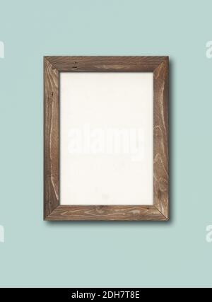 Old rustic wooden picture frame hanging on a light blue wall Stock Photo