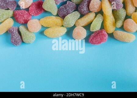 A colorful assortment of sugar-covered sweets. Top view on blue background and space at the bottom to insert a text. Stock Photo