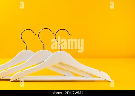 Horizontal color image with a front view of a white hangers on a yellow background. Sales clothes concept. Stock Photo