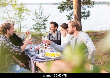 Friends enjoying while having lunch at lakeshore Stock Photo