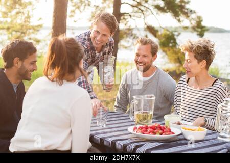 Group of friends enjoying while having lunch at lakeshore Stock Photo