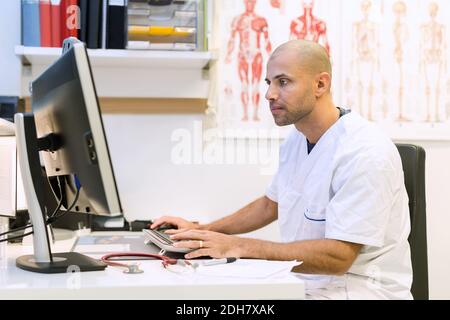 Male orthopedic doctor using computer at desk in clinic Stock Photo