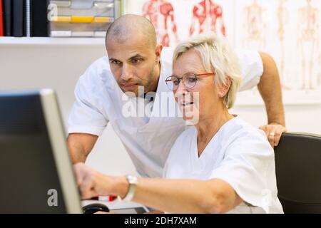 Doctors discussing over computer in office at orthopedic clinic Stock Photo