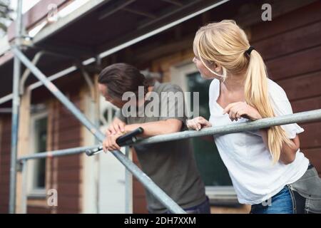 Couple leaning on scaffolding outside house during home improvement Stock Photo