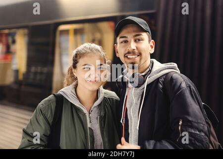 Portrait of happy young couple standing at subway station Stock Photo