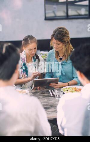 Two women using digital tablet at outdoor cafe Stock Photo