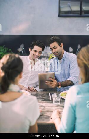 Two men using digital tablet at outdoor cafe Stock Photo