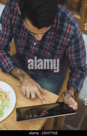 Man using digital tablet while having lunch at cafe Stock Photo