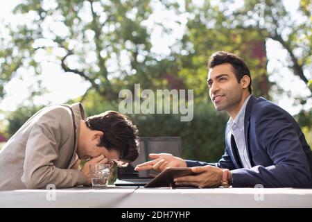 Confused businessmen being stumbled at outdoor cafe Stock Photo