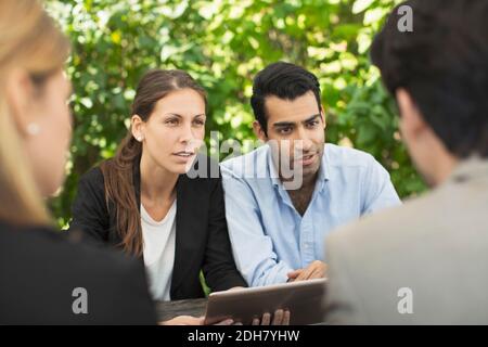Business couples discussing using digital tablet at outdoor cafe Stock Photo