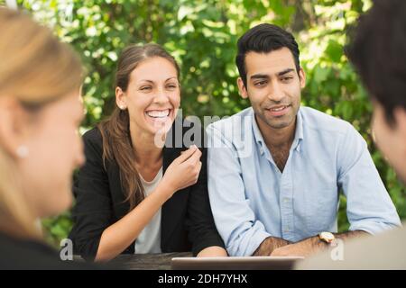 Happy business couples discussing using digital tablet at outdoor restaurant Stock Photo