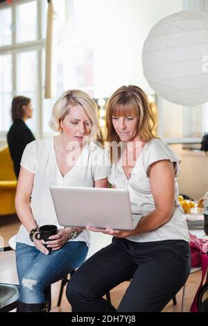 Businesswomen using laptop in office Stock Photo