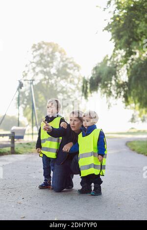 Teacher showing something to children while pointing away at playground Stock Photo