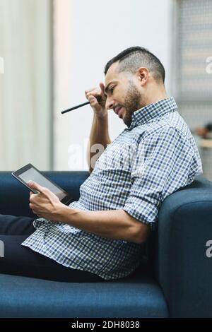 Worried businessman using digital tablet on sofa at office Stock Photo