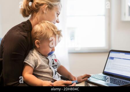 Mother with baby boy using laptop at home Stock Photo