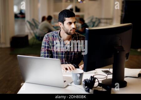Businessman working late on desktop PC in creative office Stock Photo