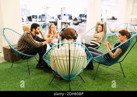 Creative business people using technologies at office canteen Stock Photo